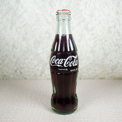 No Location vintage 6-1/2 oz full Coke bottle with white painted graphics and red Coca Cola Classic cap: Front