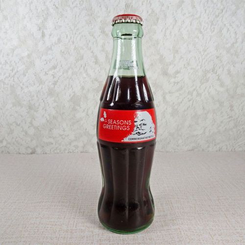 1991 Seasons Greetings full Classic Coke bottle. Santa’s face in white and black on a red background: Front